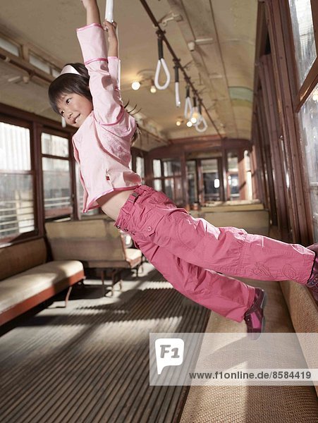 Mädchen hängt an Griffen in einem Wagen in einem Zug