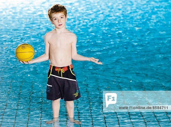 Junge mit gelbem Ball im Schwimmbad