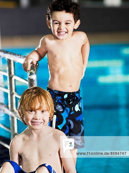 Nahaufnahme von zwei lächelnden Jungen  die am Swimmingpool posieren.
