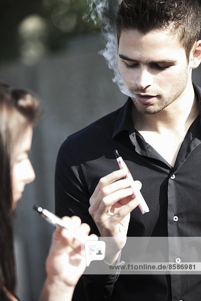 Frankreich  junges Paar  das elektronische Zigaretten raucht.