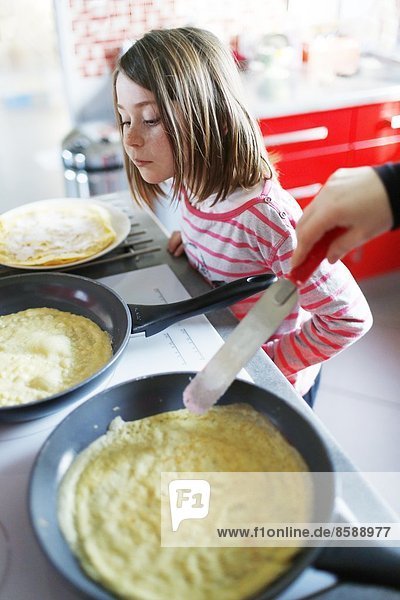 Ein kleines Mädchen macht Crêpes.