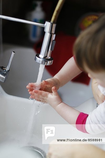 Ein kleines Mädchen wäscht sich die Hände.