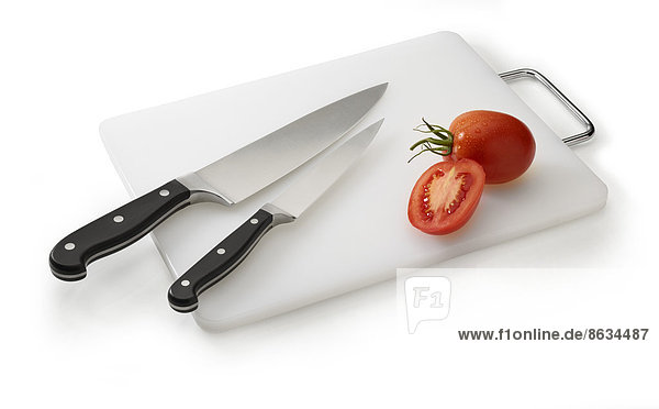Zwei Messer auf weißem Brett mit Tomaten