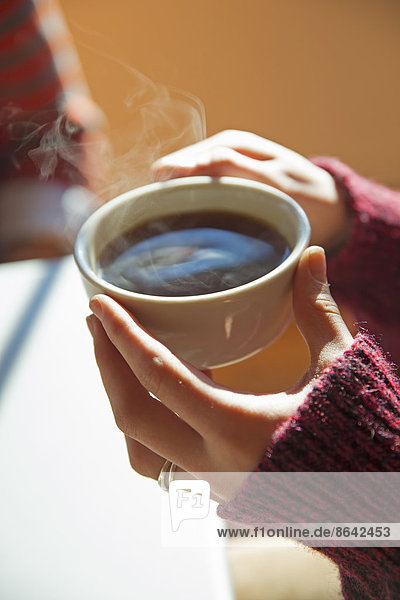 A woman holding a cup of hot coffee in her hands.