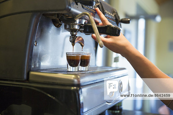 A young woman making coffee using a large coffee machine.