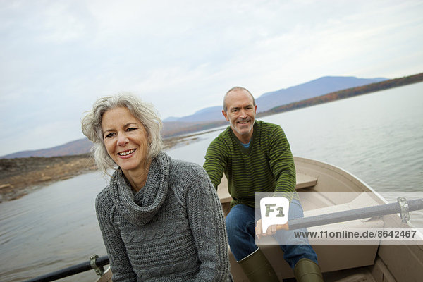 A couple  man and woman sitting in a rowing boat on the water on an autumn day.