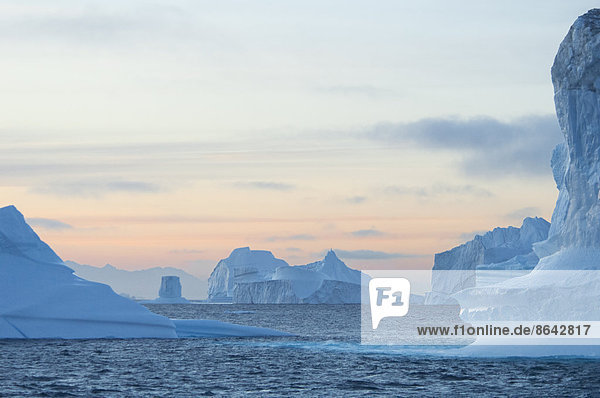 Hohe skulptierte Eissäulen  die in einem Fjord im Meer treiben.