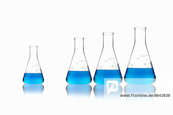 Konische wissenschaftliche Glaskolben mit blauen Flüssigkeiten. Aufgereiht in der Reihenfolge ihrer Größe  mit einem Abstand.