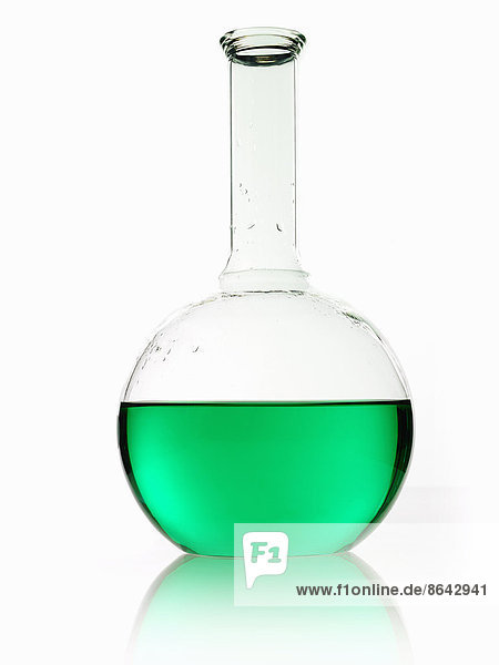 Ein runder Glaskolben für wissenschaftliche Chemikalien mit einem langen Trichterhals  der grüne Flüssigkeit enthält.