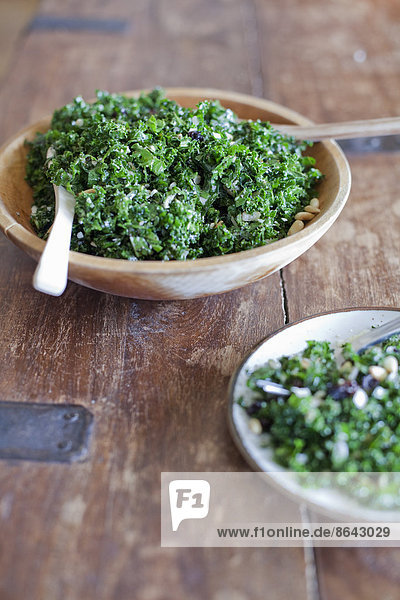 Eine hölzerne Küchentischplatte. Zwei Teller mit frischem grünen Salatgemüse. Frische Bio-Lebensmittel.