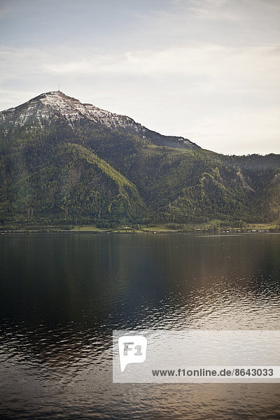 Ein Berggipfel  der einen See überragt und ein Spiegelbild auf der ruhigen Wasseroberfläche erzeugt.