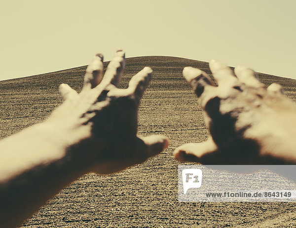 Hands extending reaching out towards ploughed farmland  near Pullman  Washington  USA