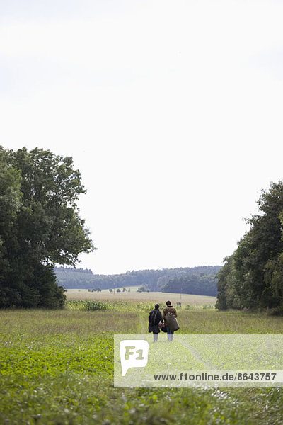 Young couple walking through field
