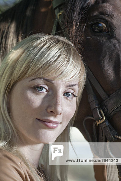 Porträt einer jungen Frau mit Pferd  lächelnd