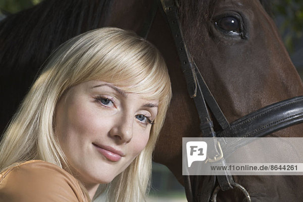Porträt einer jungen Frau mit Pferd,  lächelnd