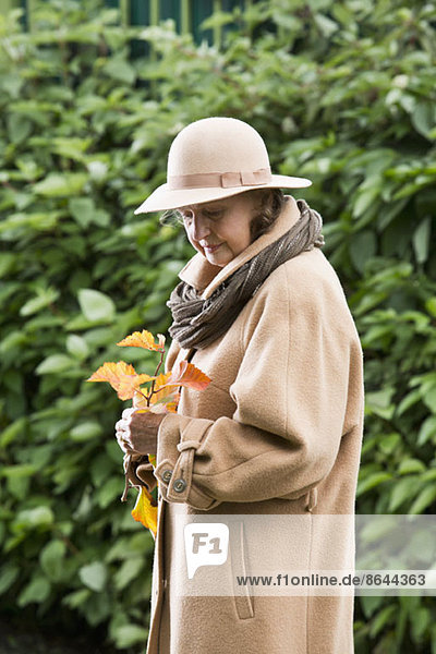 Seniorin schaut auf Herbstlaub