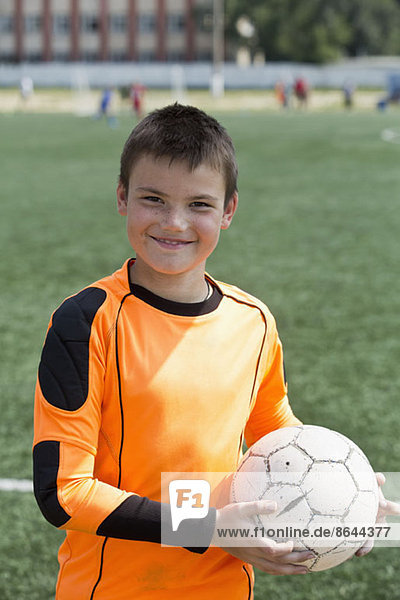 Porträt eines Jungen  der Fußball hält  lächelnd