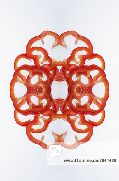 A digital composite of mirrored images of slices of red bell pepper