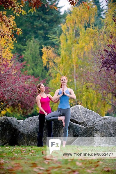 Yogalehrerin unterrichtet junge Frau im Wald