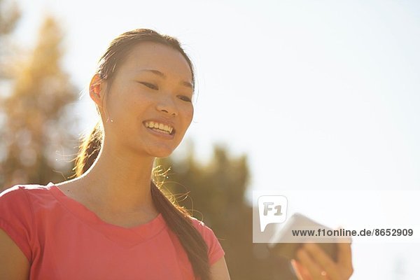 Junge Frau im Park schaut auf Handy