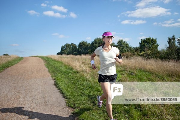 Young female runner running alongside dirt track