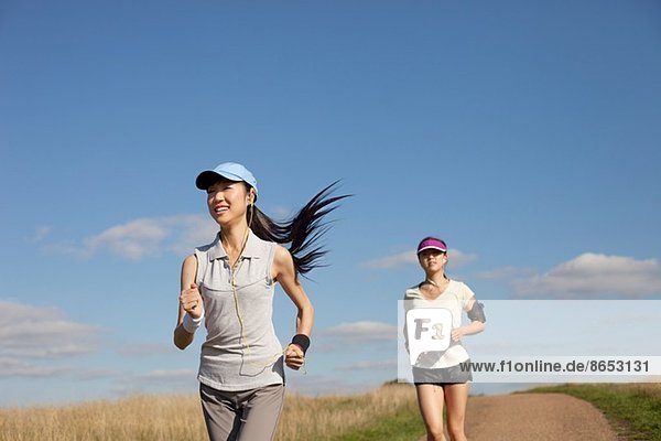 Zwei junge Frauen  die auf einem Feldweg laufen.