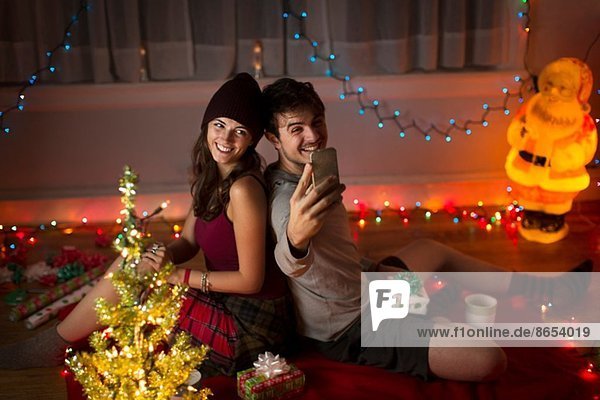 Junges Paar  das sich zu Weihnachten im Wohnzimmer niederlässt