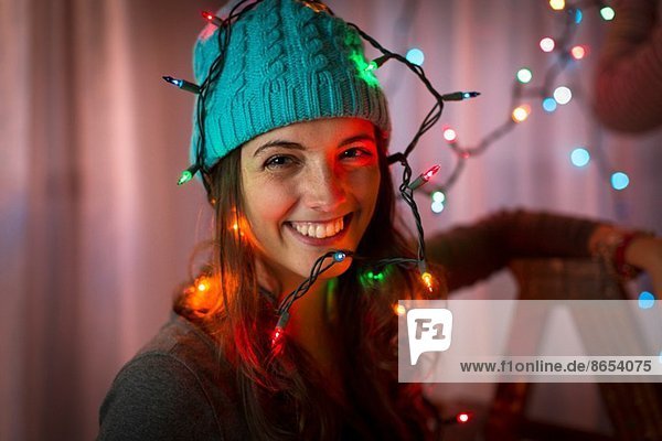 Porträt einer jungen Frau in weihnachtliche Lichter gehüllt