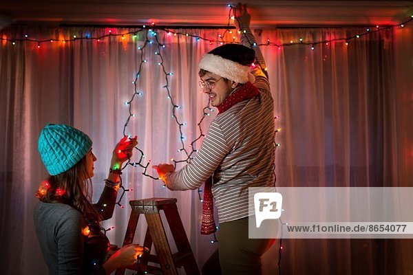 Junges Paar mit Lichterketten an Weihnachten