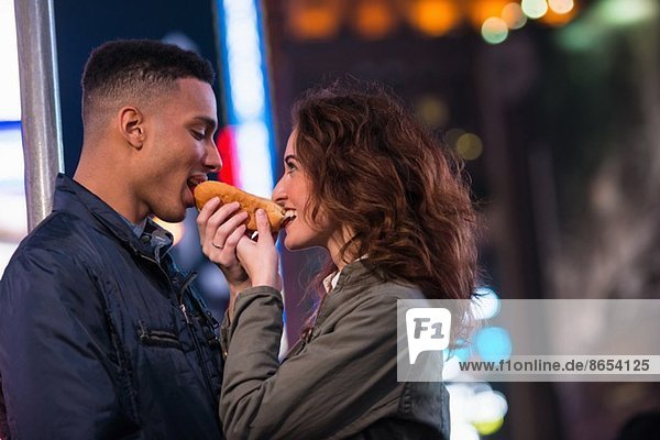 Young tourist couple sharing hotdog  New York City  USA