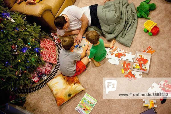 Junger Mann und Neffen spielen mit Puzzles auf dem Boden