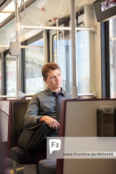 Mittlerer erwachsener Büroangestellter,  der auf der Zugfahrt gelangweilt aussieht