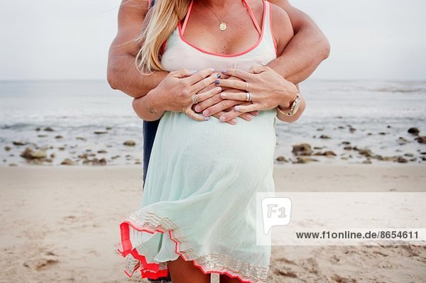 Abgeschnittenes Bild der Umarmung eines schwangeren Paares