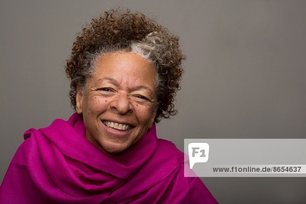 Studio-Porträt der glücklichen Seniorin in rosa Tuch