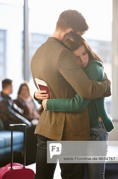 Junge Paare umarmen sich am Flughafen