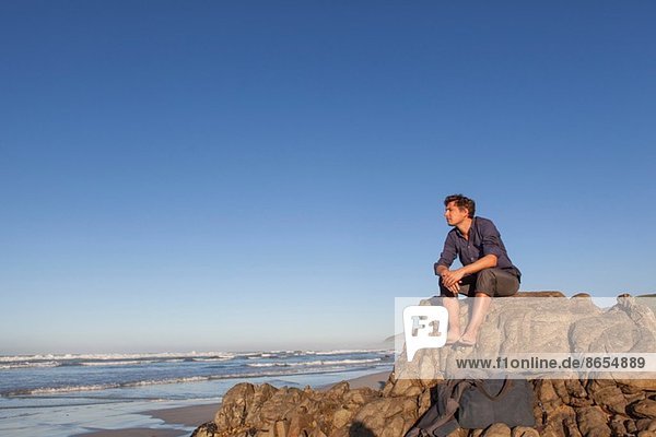 Man sitting on rock at seaside