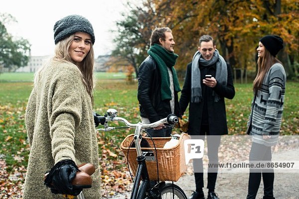 Junge Frau mit Fahrrad  Freunde im Hintergrund