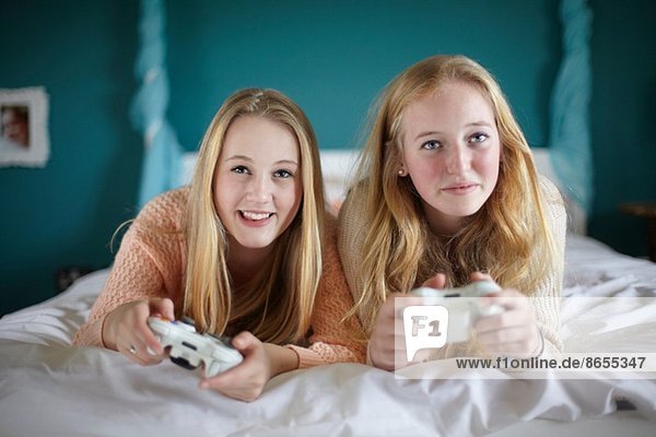 Two teenage girls playing on computer game in bedroom