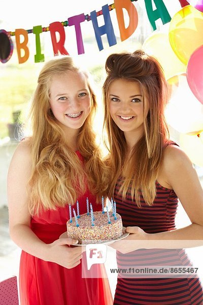 Zwei Teenager-Mädchen mit Geburtstagskuchen
