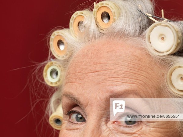 Nahaufnahme Studio-Porträt einer älteren Frau in Haarrollen