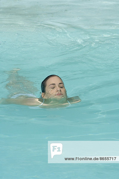 Junge Frau schwimmt im Schwimmbad  Augen geschlossen