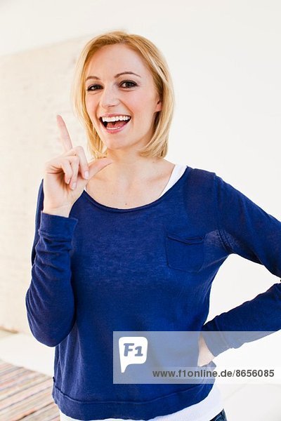 Studio-Porträt einer jungen Frau  die mit dem Finger zeigt