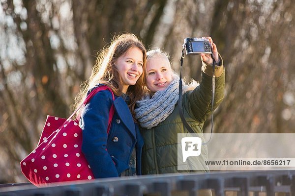 Teenage girls photographing themselves with camera