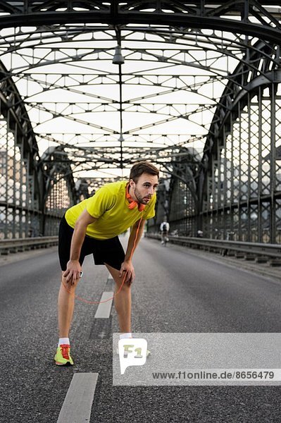 Junger Läufer macht Pause auf der Brücke