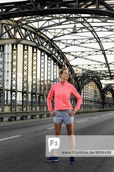 Young female runner exercising on bridge