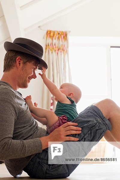 Vater mit Hut und Baby auf dem Schoß