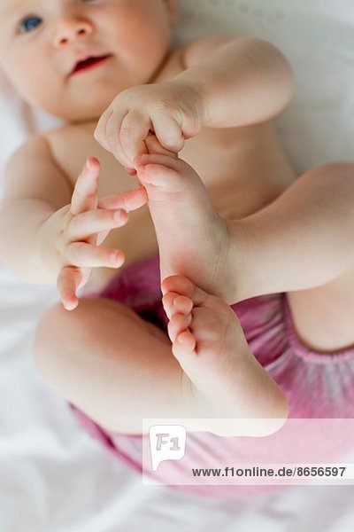 Kleines Mädchen spielt mit den Füßen