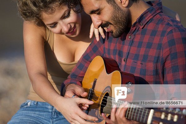 Junges Paar  Mann spielt Gitarre