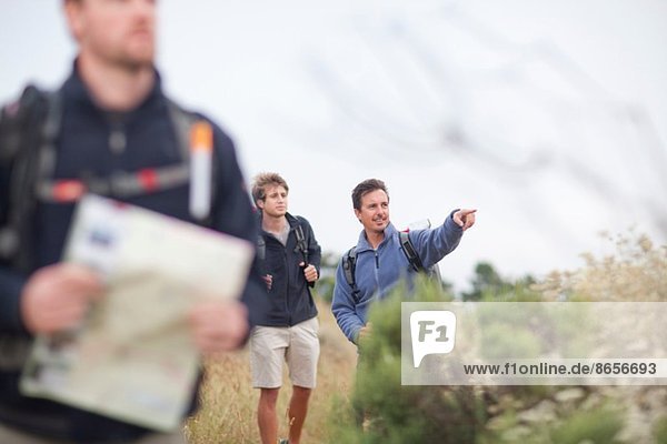 Drei männliche Wanderer mit Rucksack und Karte