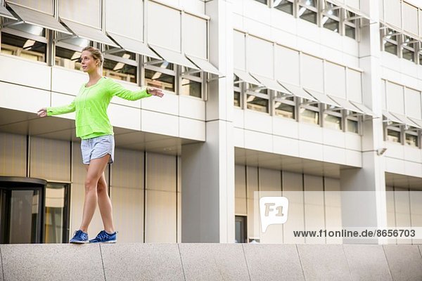 Young woman walking on wall